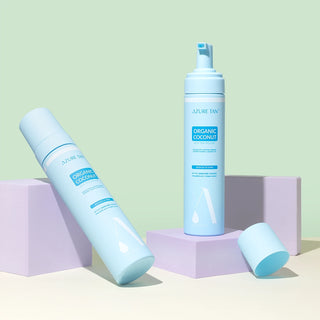 Two bottles of Azure Tan Organic Coconut product on a pastel green and purple background