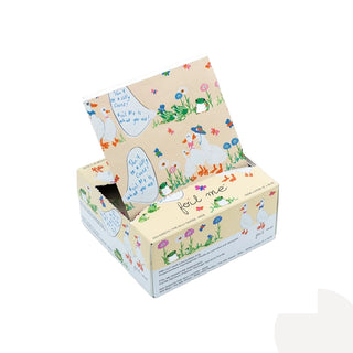 A decorative cardboard display box with a hinged lid, featuring a whimsical illustration of white ducks in a field of flowers on a light beige background. The box is shown open against a plain white background.