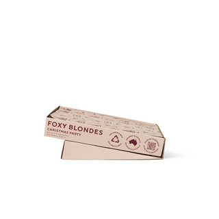 A rectangular cardboard box for hair foil, shown at an angle on a plain white background. The box is light beige with dark red text reading 'FOXY BLONDES CHRISTMAS PARTY' and small printed illustrations and icons along the top.