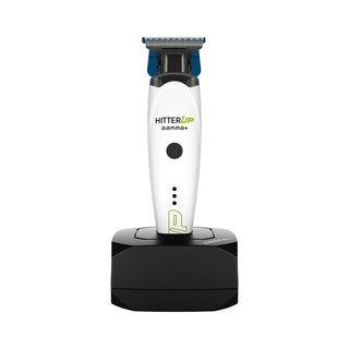 A HitterUp Gamma+ cordless electric trimmer with a white body, blue and black accents, standing upright on a black charging dock against a plain white background.