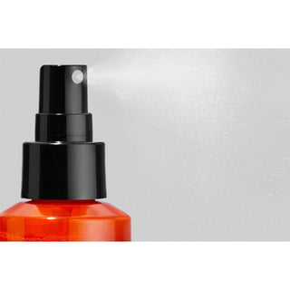 Black spray nozzle on a red bottle against a gray background