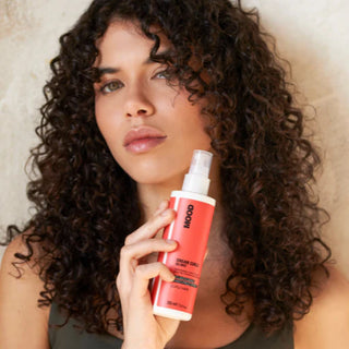 Woman holding a red spray bottle with 'MOOD' branding against a neutral background
