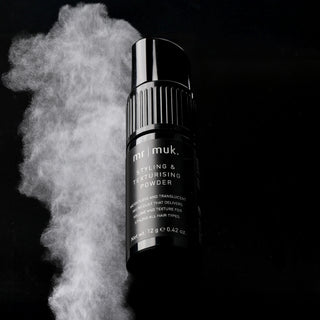 mr muk styling and texturizing powder with white powder cloud on black background