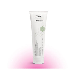 A white squeeze tube of muk. haircare TREAT plus+ Bond Restoring Mask, featuring a light green geometric pattern and the number 2, set against a white background with a soft pink glow at the bottom.