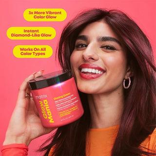 Woman with vibrant red hair holding a pink hair product container against a pink background