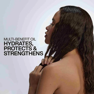 Woman with long, wavy hair touching her shoulder, with text about a multi-benefit oil.